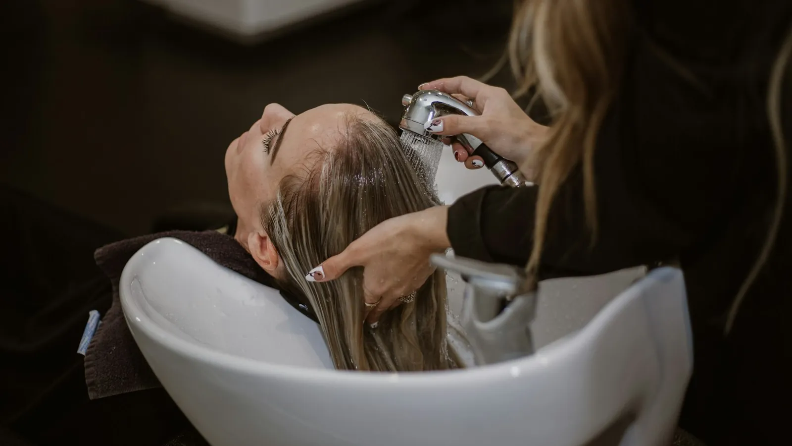 Cabeleireira lavando o cabelo de cliente em salão de bairro